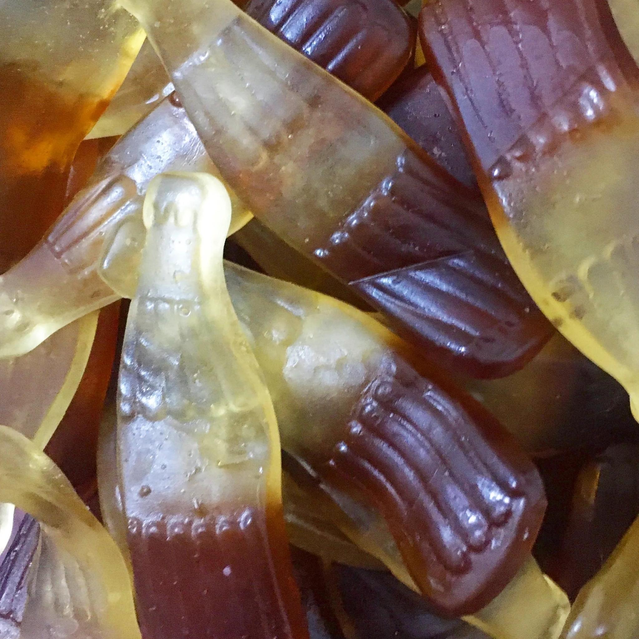 Close-up of gummy candy shaped like bottles with a gradient of colors.