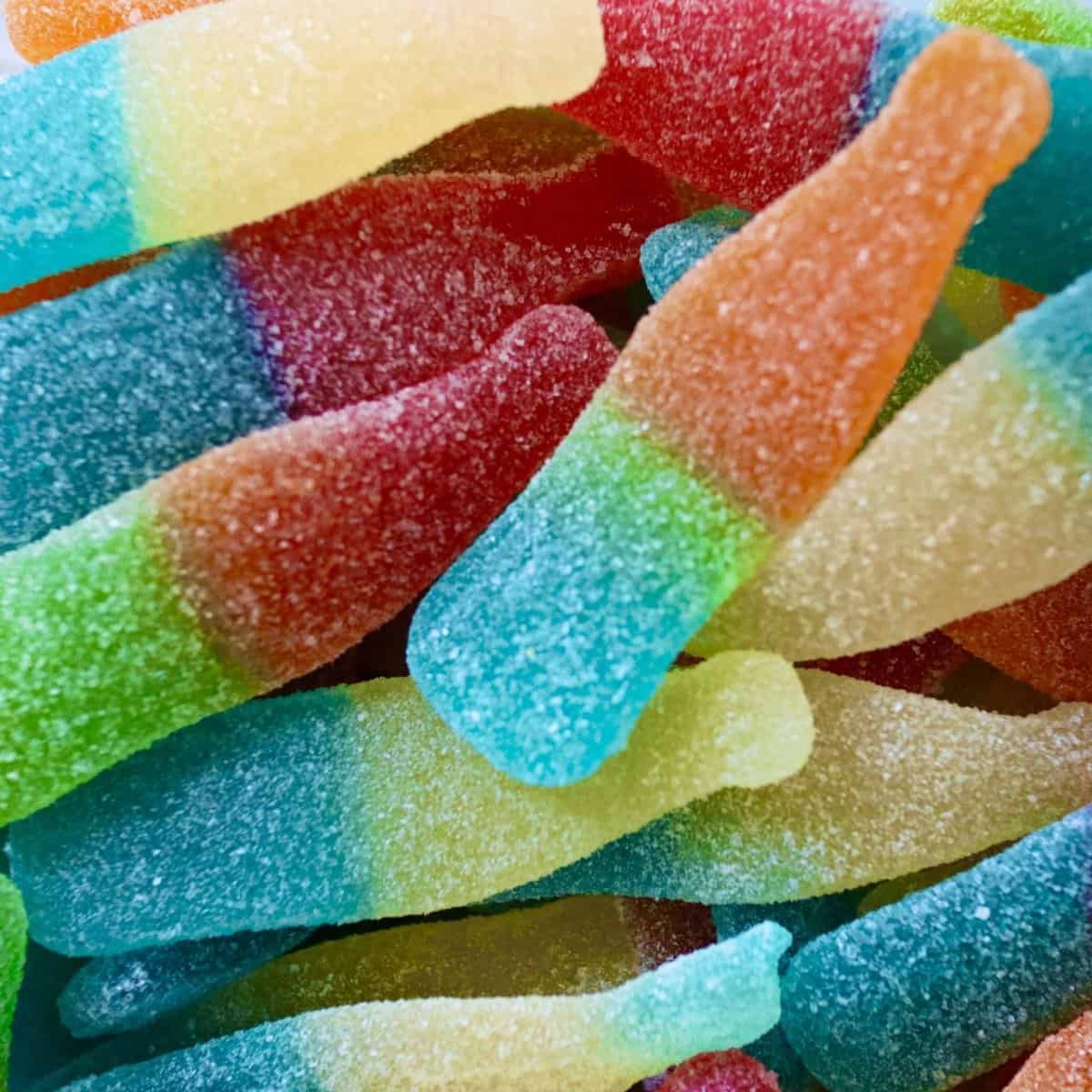 Close-up of colourful gummy bottles with a multicoloured background